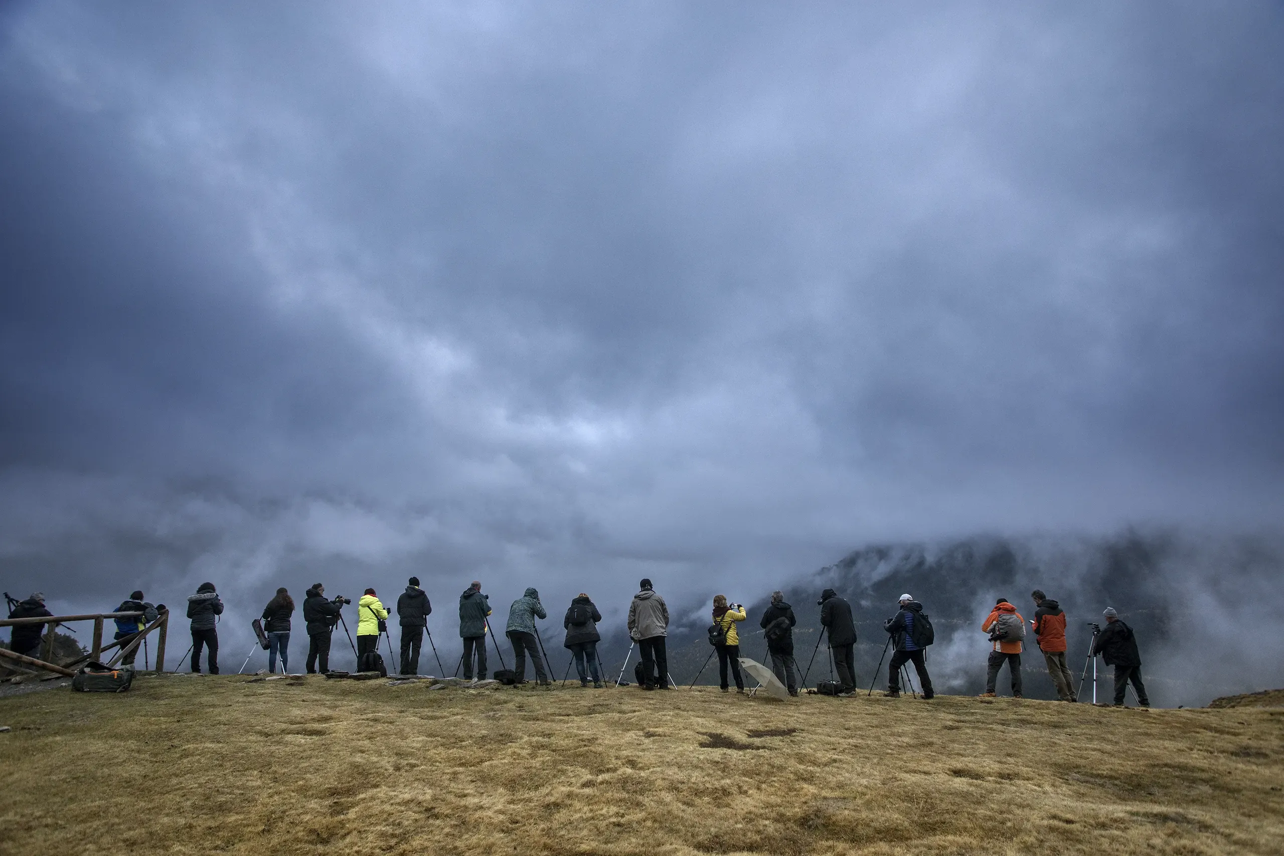 Fotògrafs de paisatge amb trípodes sota un cel de tempesta